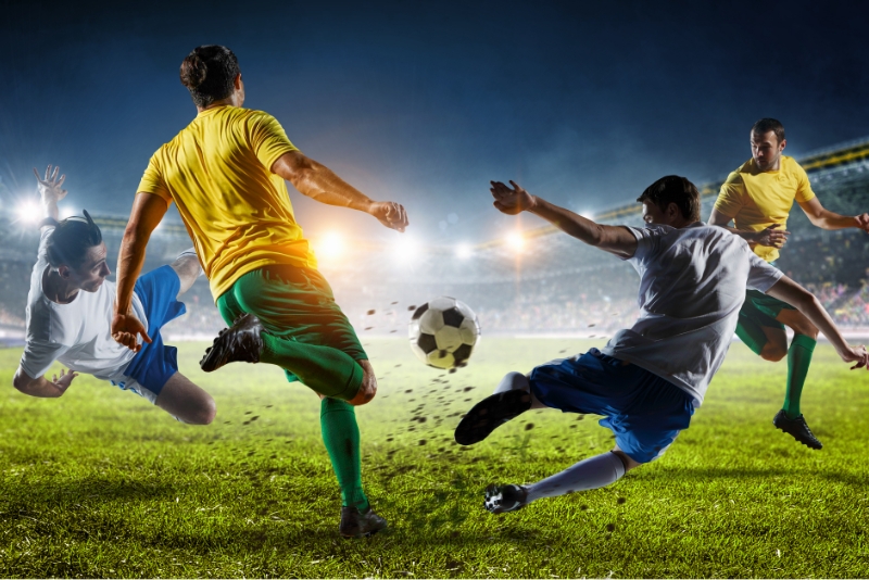 Men playing soccer with the ball about the hit a man in the face and casue nasal fracture