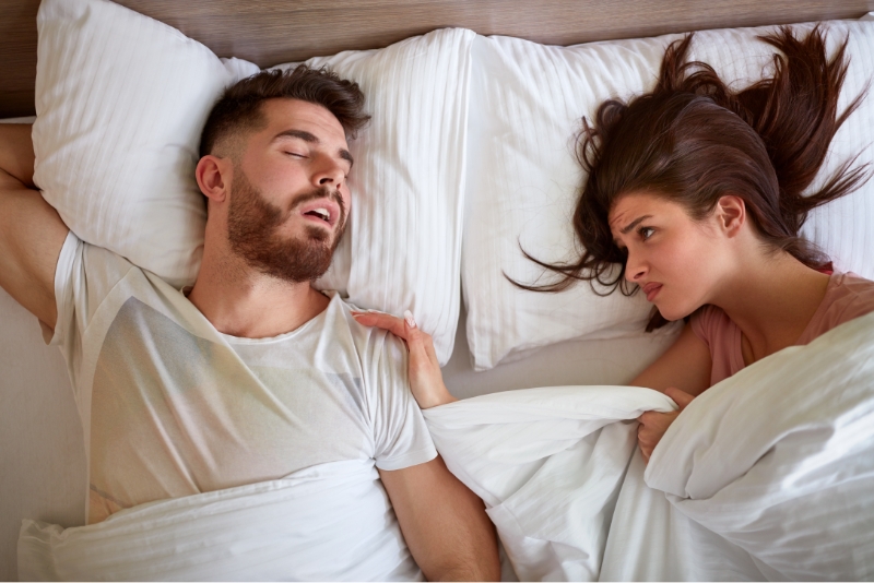 Man snoring and unhappy woman in bed